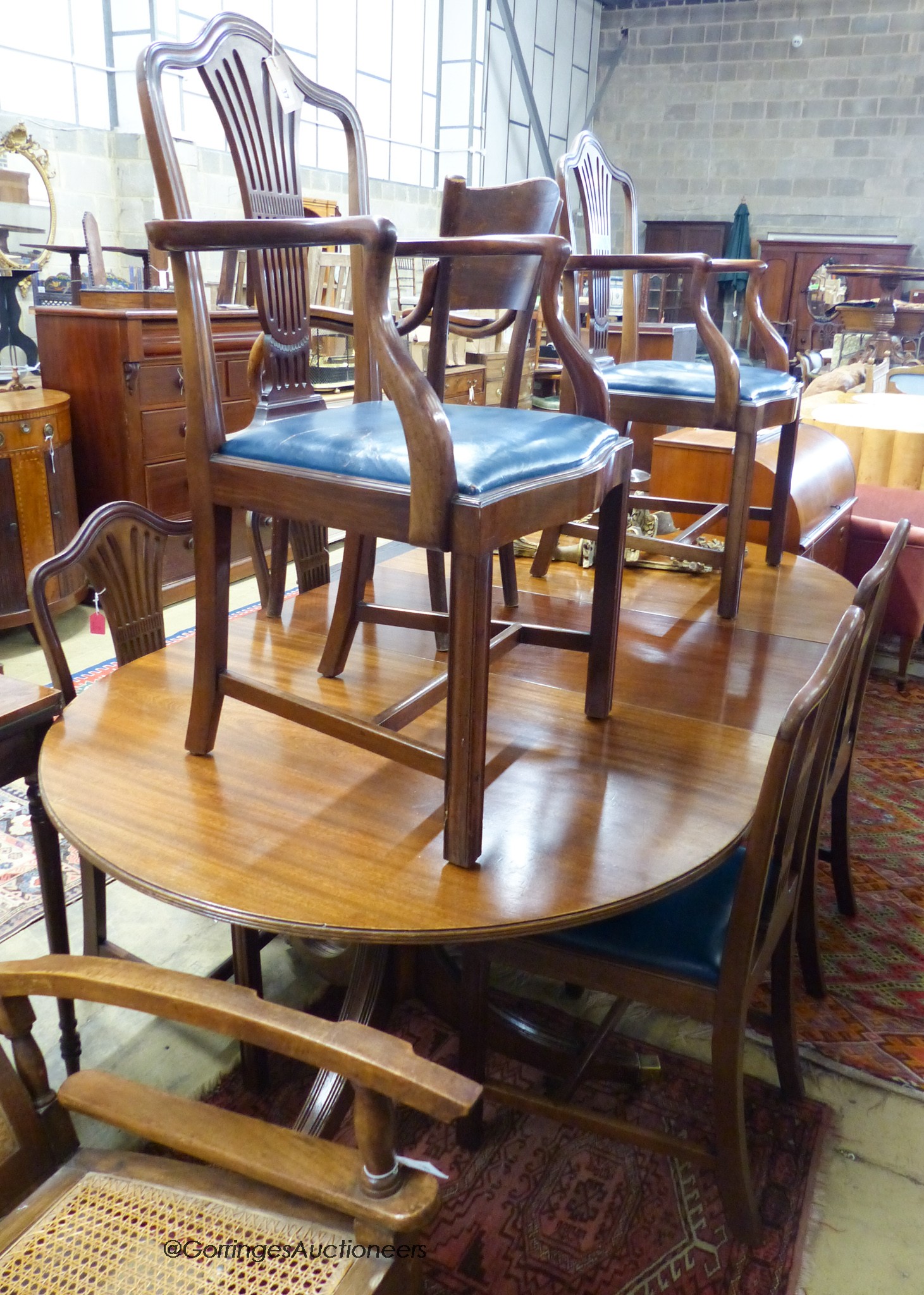 A set of six Hepplewhite style mahogany dining chairs (two with arms) and a George III style mahogany D-end two-pillar dining table